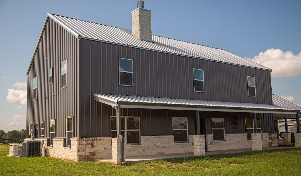 Completed Texas barndominium with covered porch, residential windows, and full exterior finish