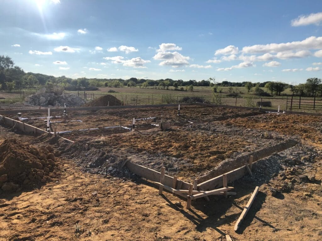 Concrete foundation forms and plumbing stub-outs on a cleared Texas lot